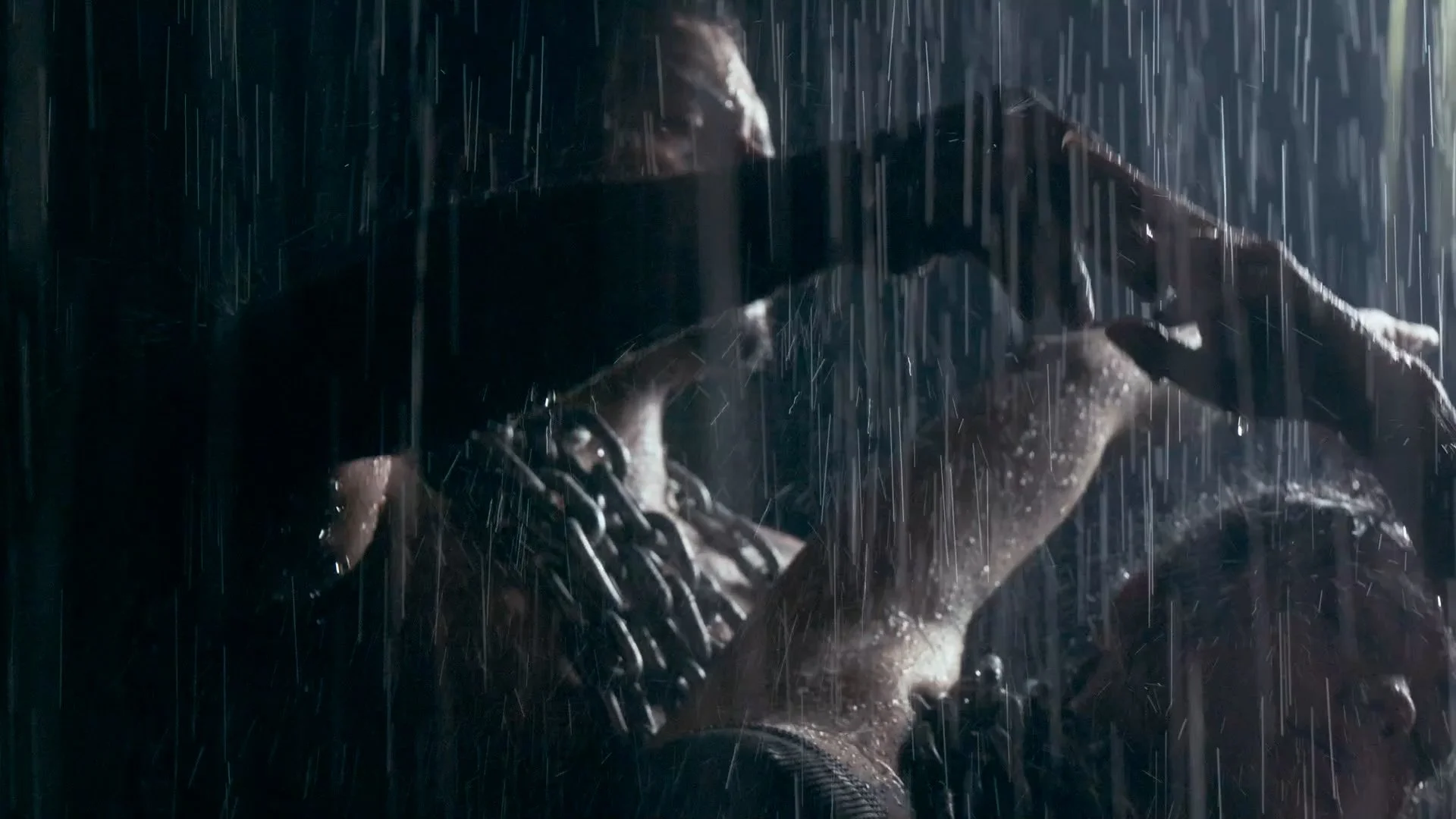 Person in rain with chains around their neck, holding a sword in a dark, wet environment.