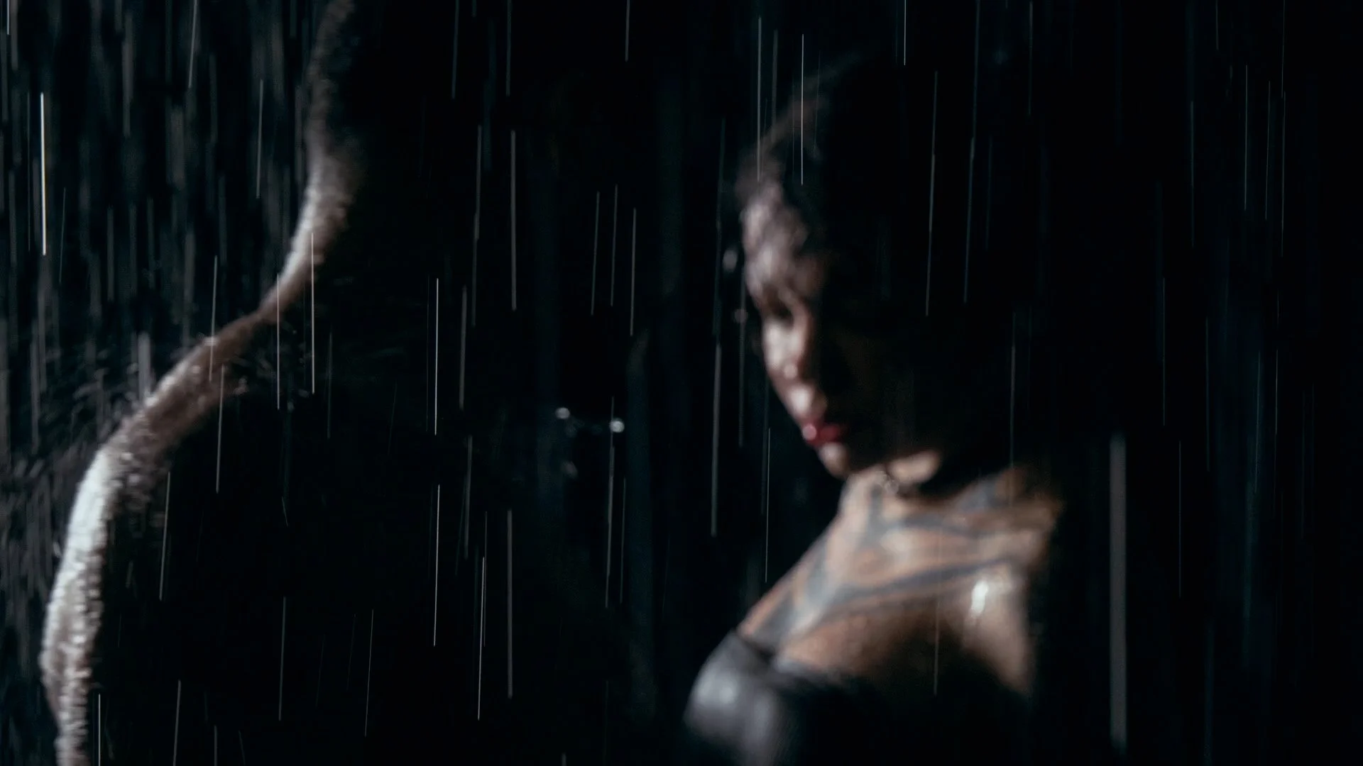 A woman in rain, partially illuminated, with a snake wrapped around her arm.