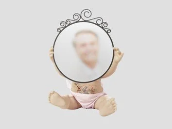 A small doll holding a round mirror reflecting a blurred face of a person.