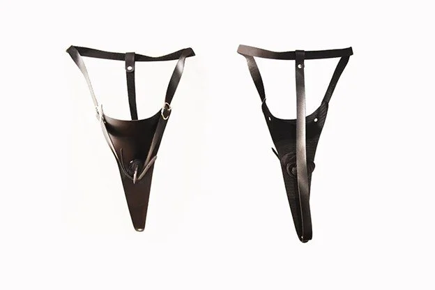 Two black leather harnesses with straps and metal rings, shown against a plain white background.