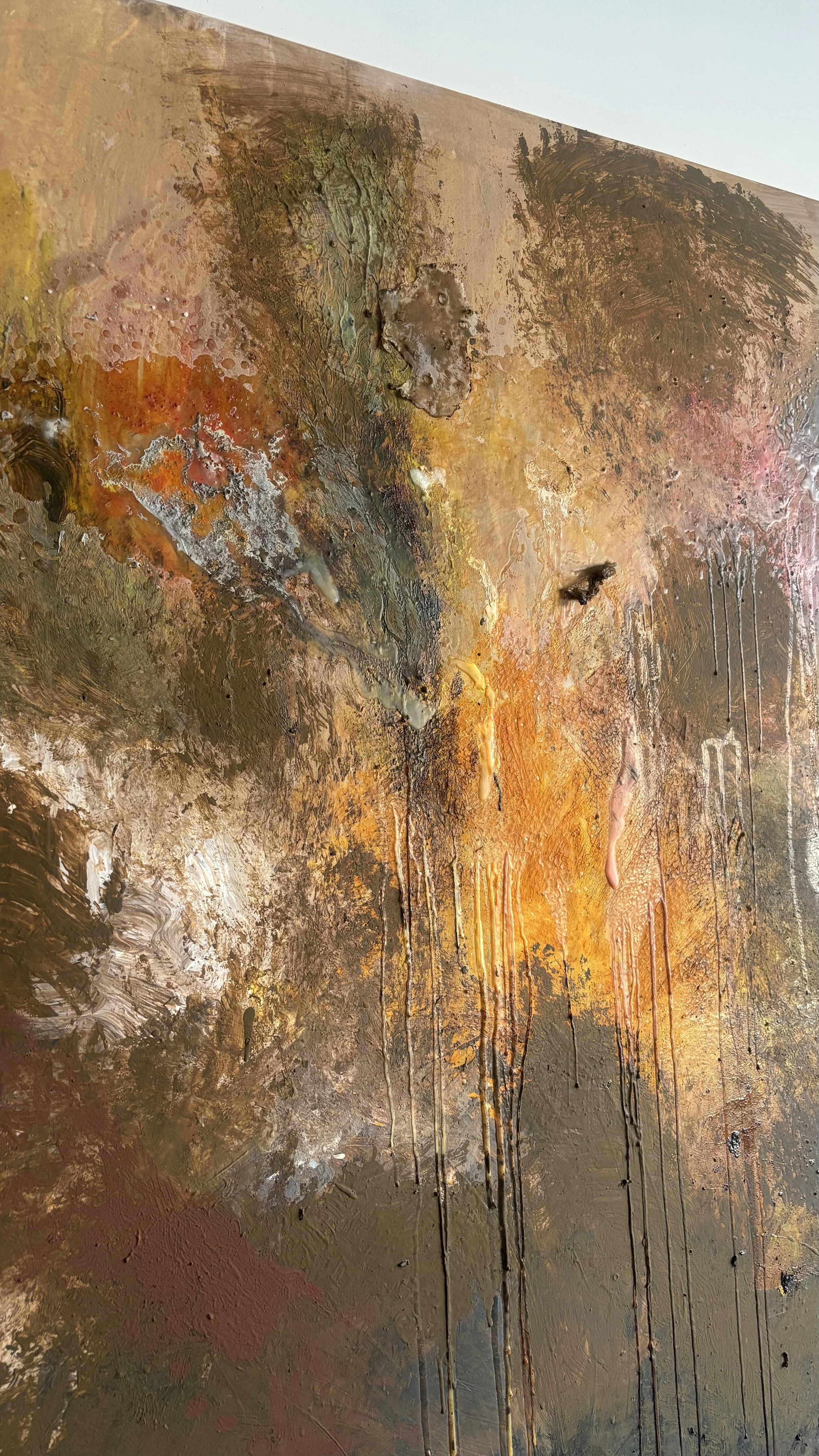 Close-up of an abstract, textured painting with warm earth tones, orange, brown, and yellow, featuring drips and layered paint.