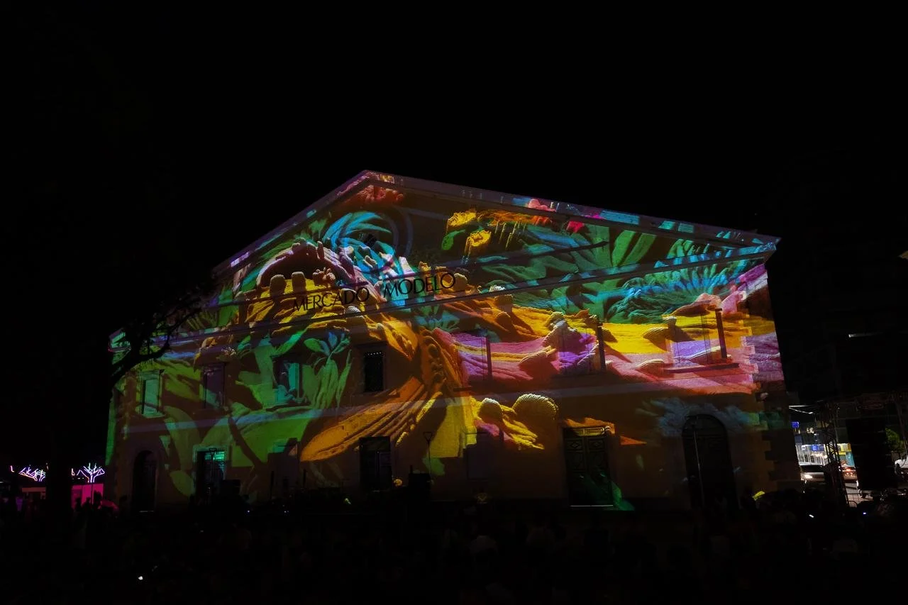 Building with colorful projections of abstract artwork on its facade at night.