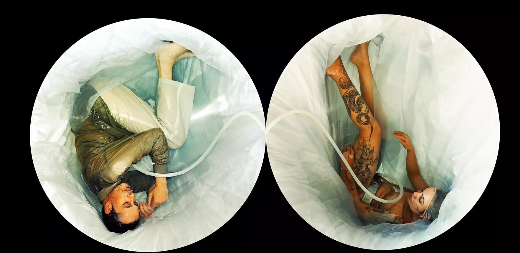Two individuals lying inside large plastic tubes, one appearing to be an older man with tattoos and the other a woman, both seemingly in a medical or artistic setting.