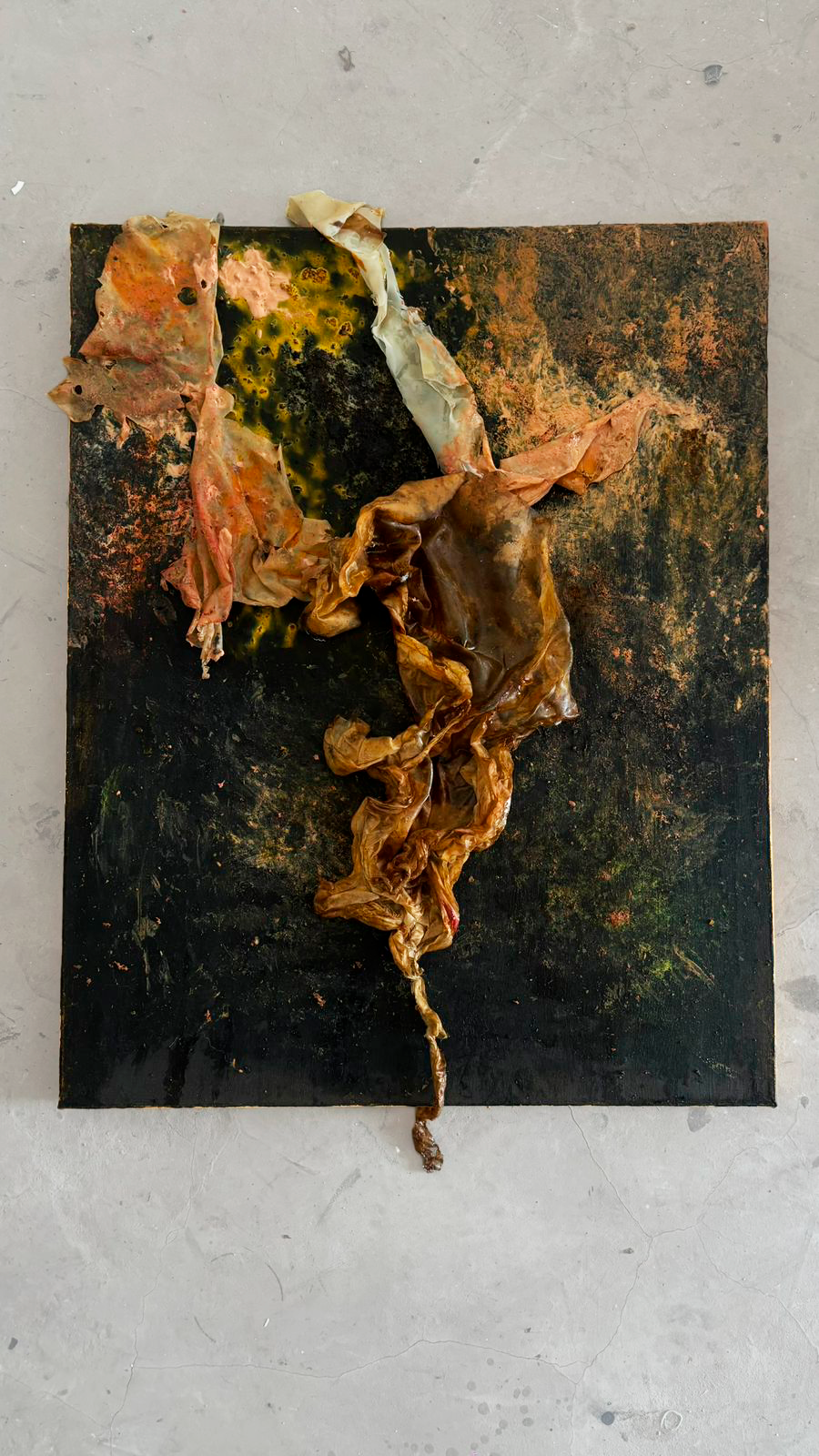 Burnt and charred remains of what appears to be crumpled, burnt paper or fabric on a blackened, rusty surface.