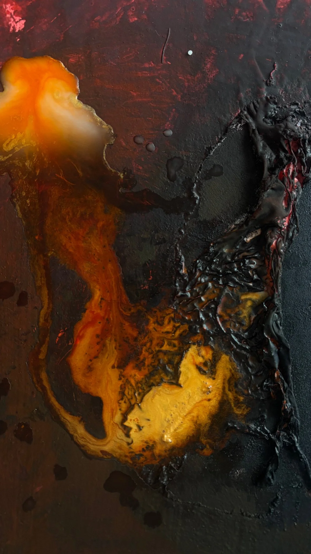 A close-up of a burnt, charred surface with melted, hardened black and orange/brown materials, possibly melted plastic or burned food.