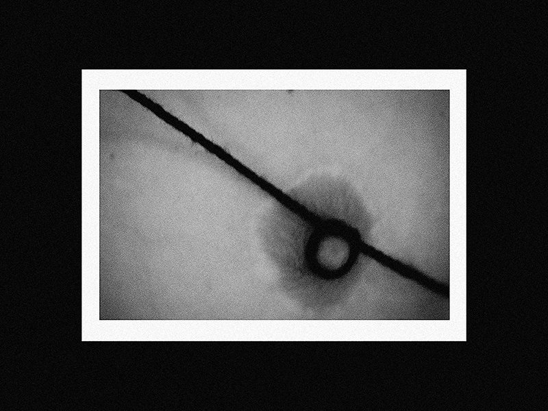 Close-up of a tiny black circle on a thin line, with a blurred background