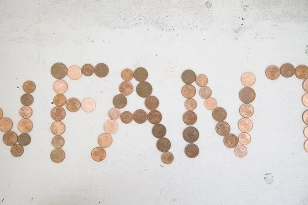 Pennies arranged to spell out the word "VOTE" on a white surface.