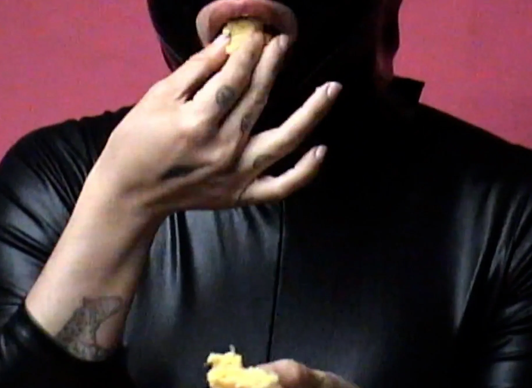 Person with tattooed hand eating food.
