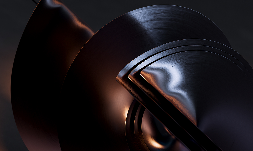 A close-up futuristic metal sculpture with curved, overlapping black and bronze-colored surfaces.