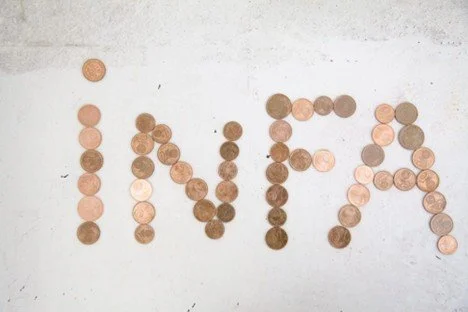 Coins arranged on a surface spelling 'MIA'.