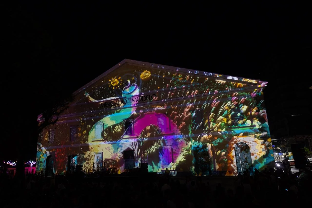 Building illuminated with colorful, abstract light projections resembling fireworks or explosions at night.