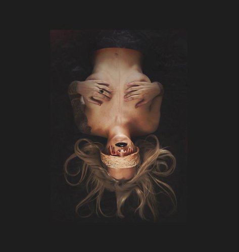 A woman with long blonde hair lying upside down, covering her eyes with her hands, and with a beige bandage wrapped around her mouth.