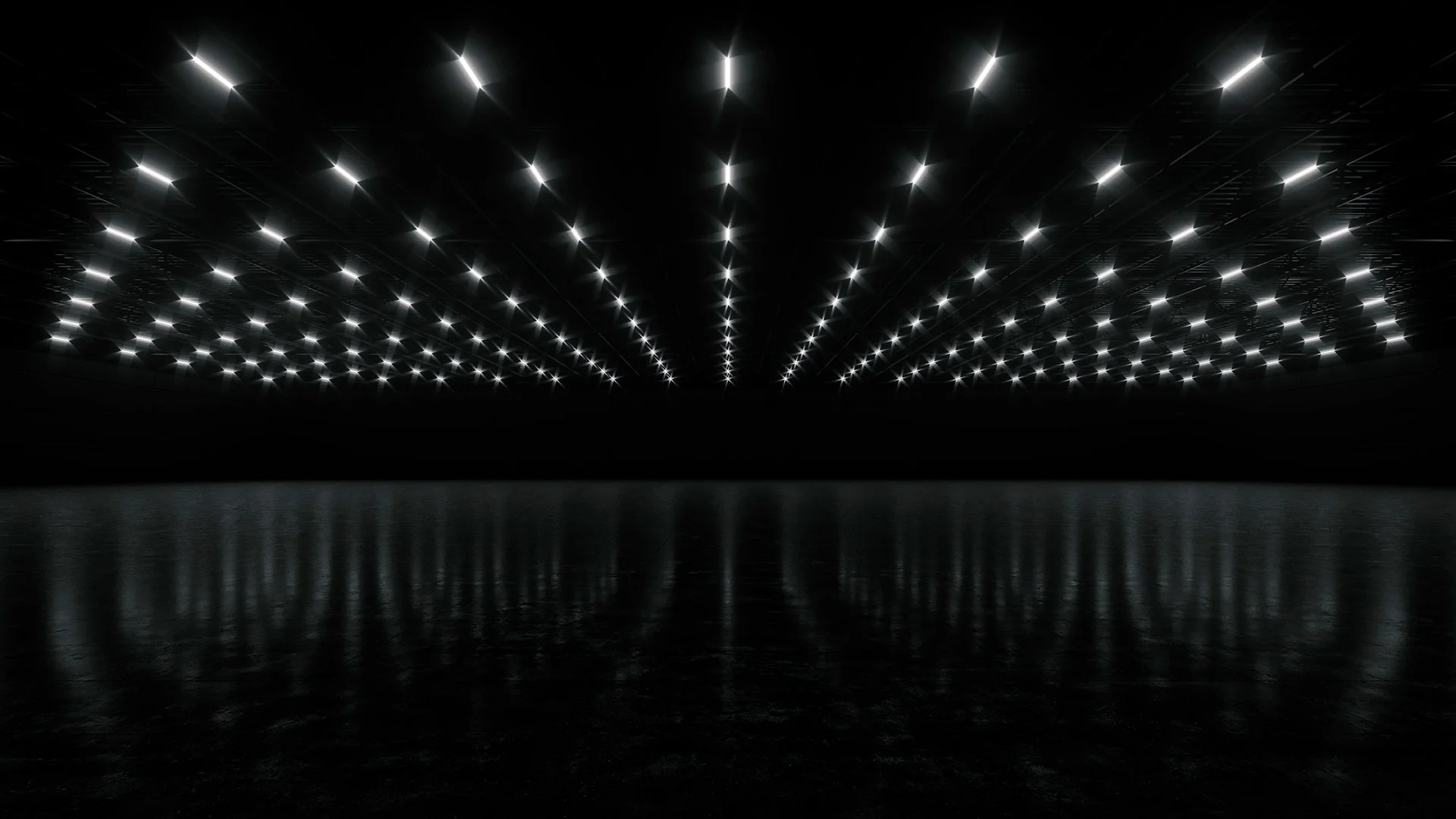 A dark, empty room with a reflective floor and a ceiling filled with evenly spaced bright white lights.