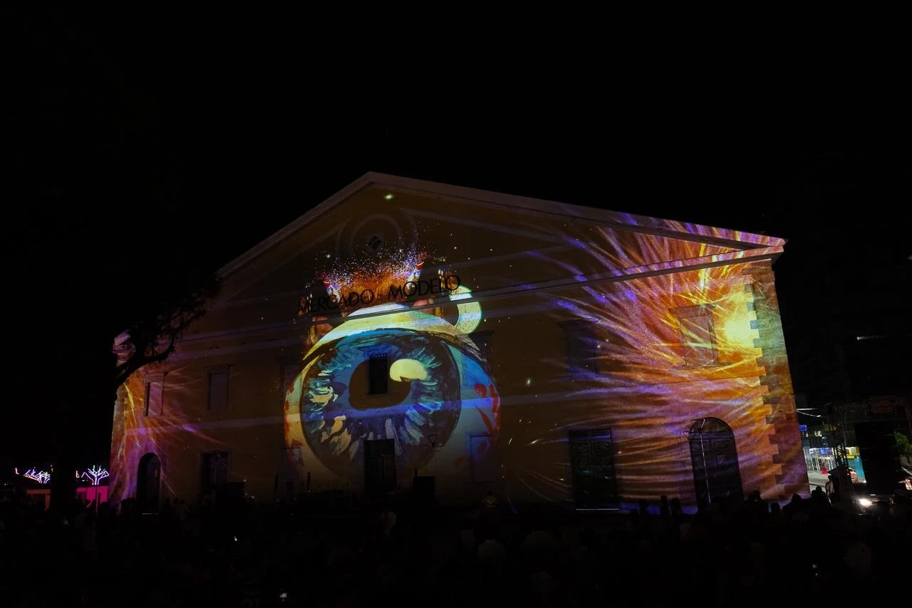 Building illuminated with colorful projection of a giant eye and abstract designs at night.