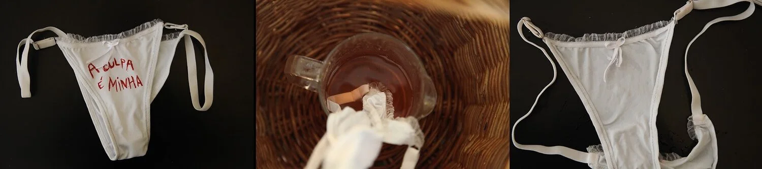 A white women's thong with red Italian embroidery, a glass mug with tea and a tea bag, and a similar white thong laid flat on a black surface.