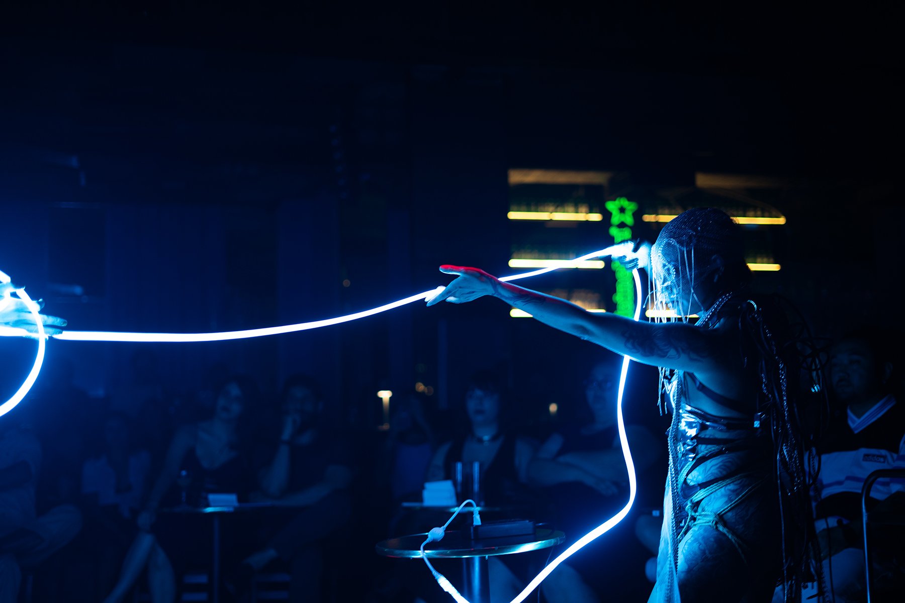 Performer in futuristic costume and LED lights performing on stage at night with audience watching