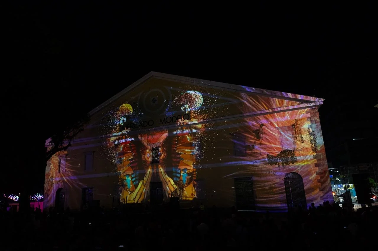 Building with colorful light projection, including celestial patterns and abstract shapes, at night.