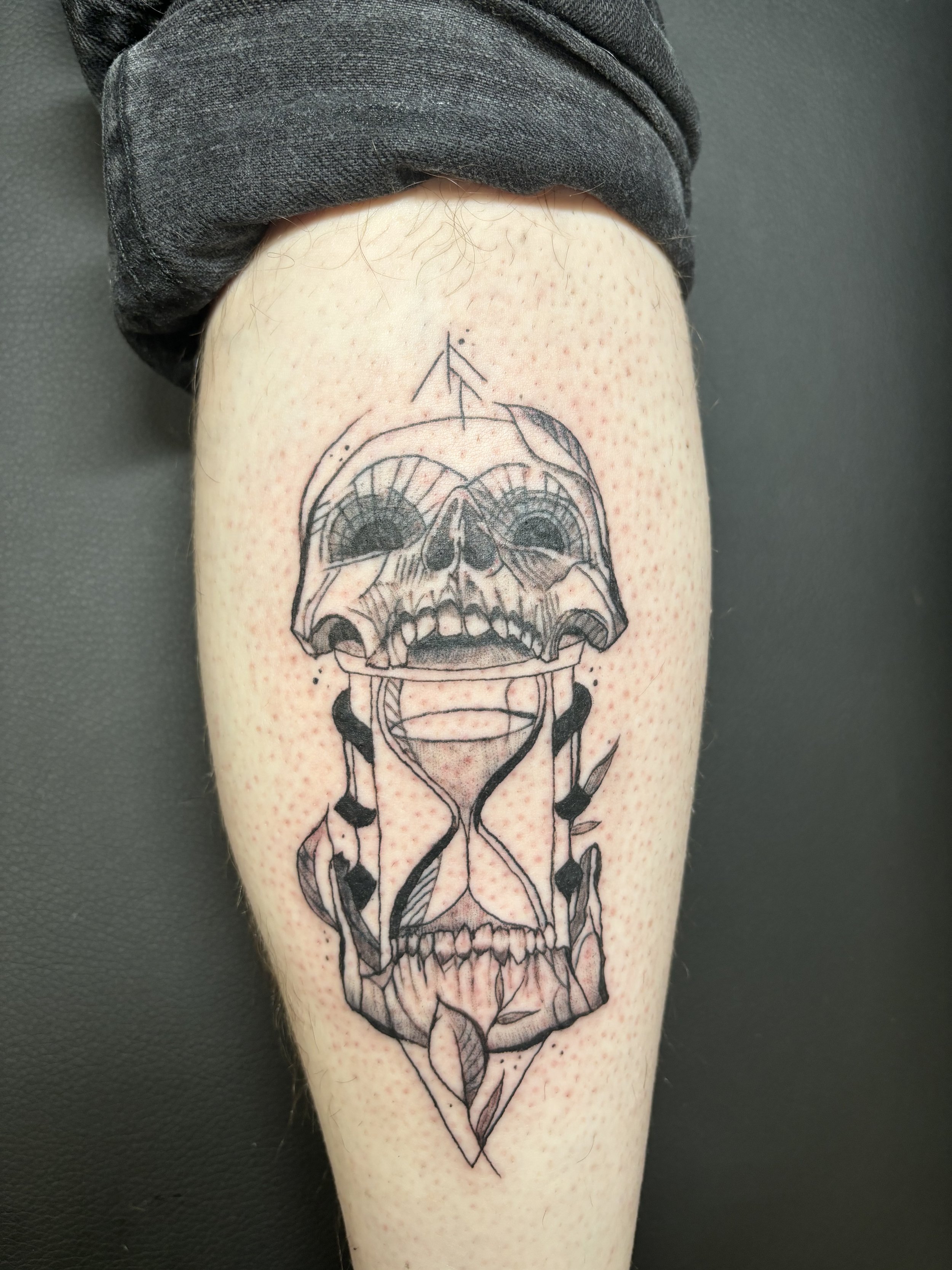  Gothic black ink skull hour glass tattoo with sketch line and plant details 