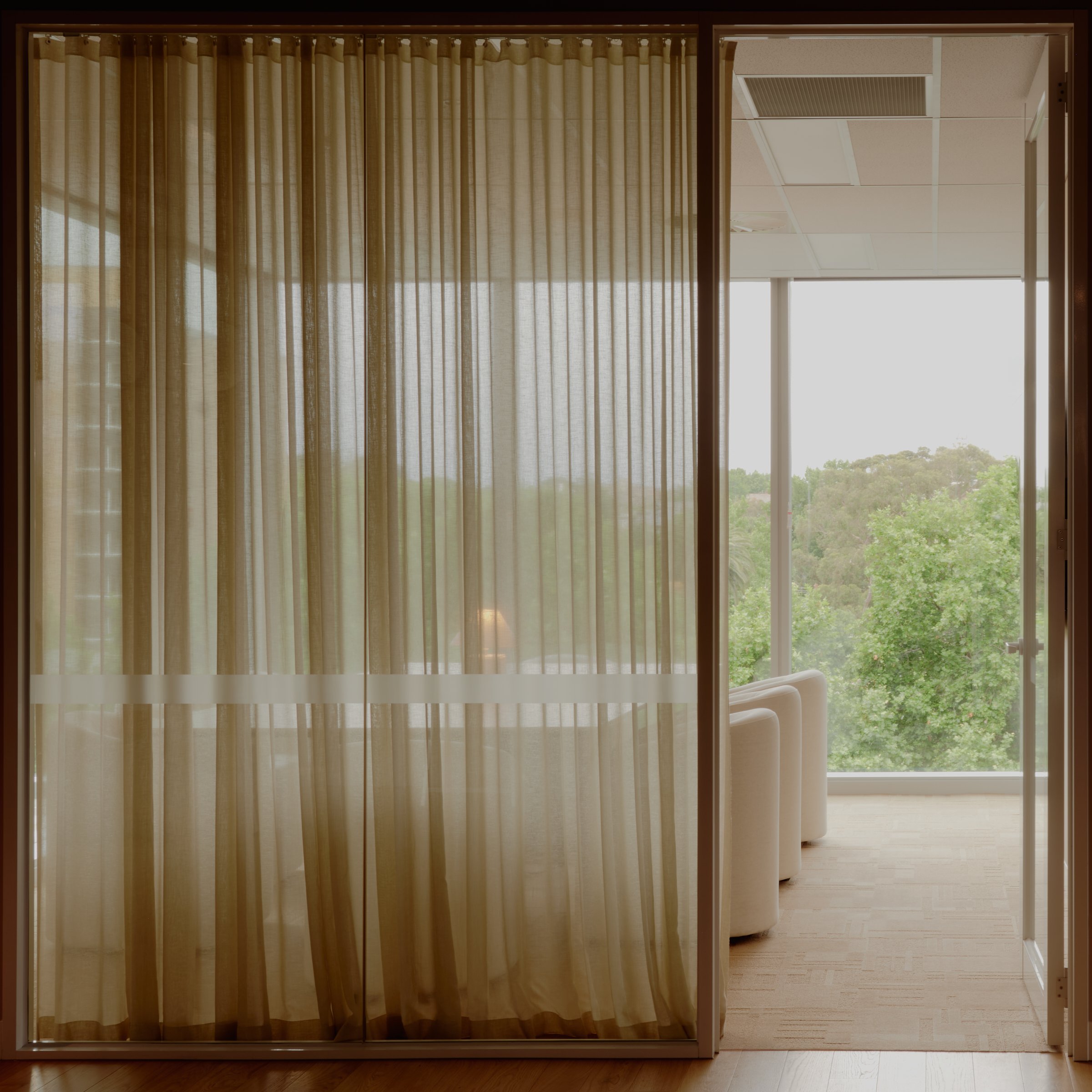 River Street office seating area with linen curtains and balcony view