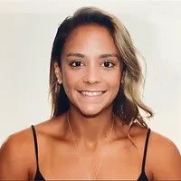 A woman with shoulder-length hair smiling and wearing a black tank top.