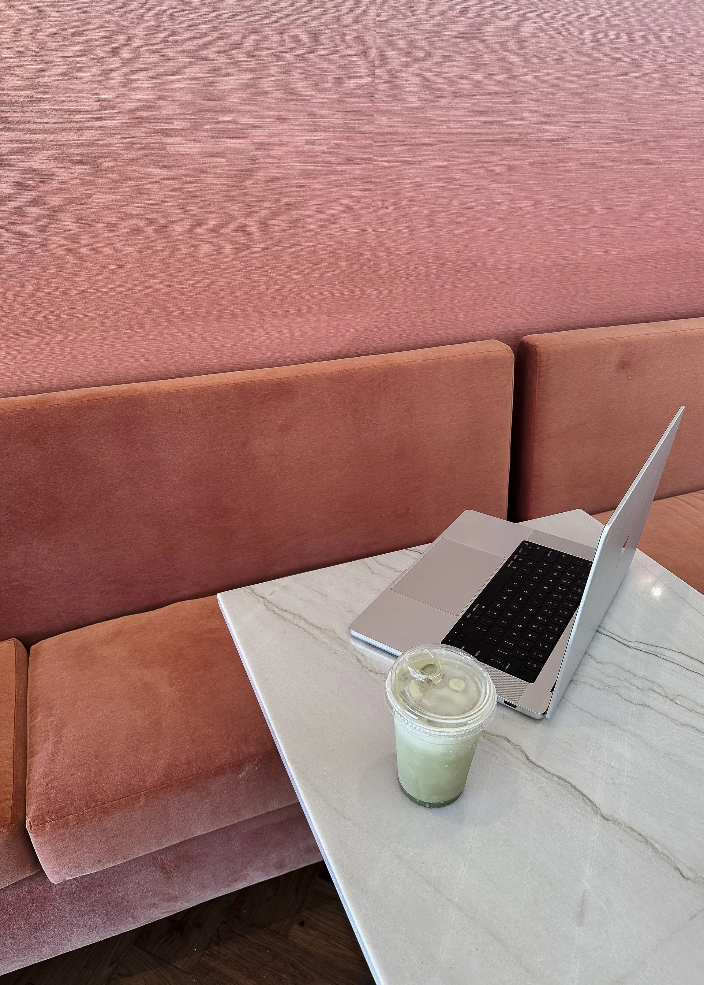 Professional web designer working on laptop set on white table near a pink velvet coach