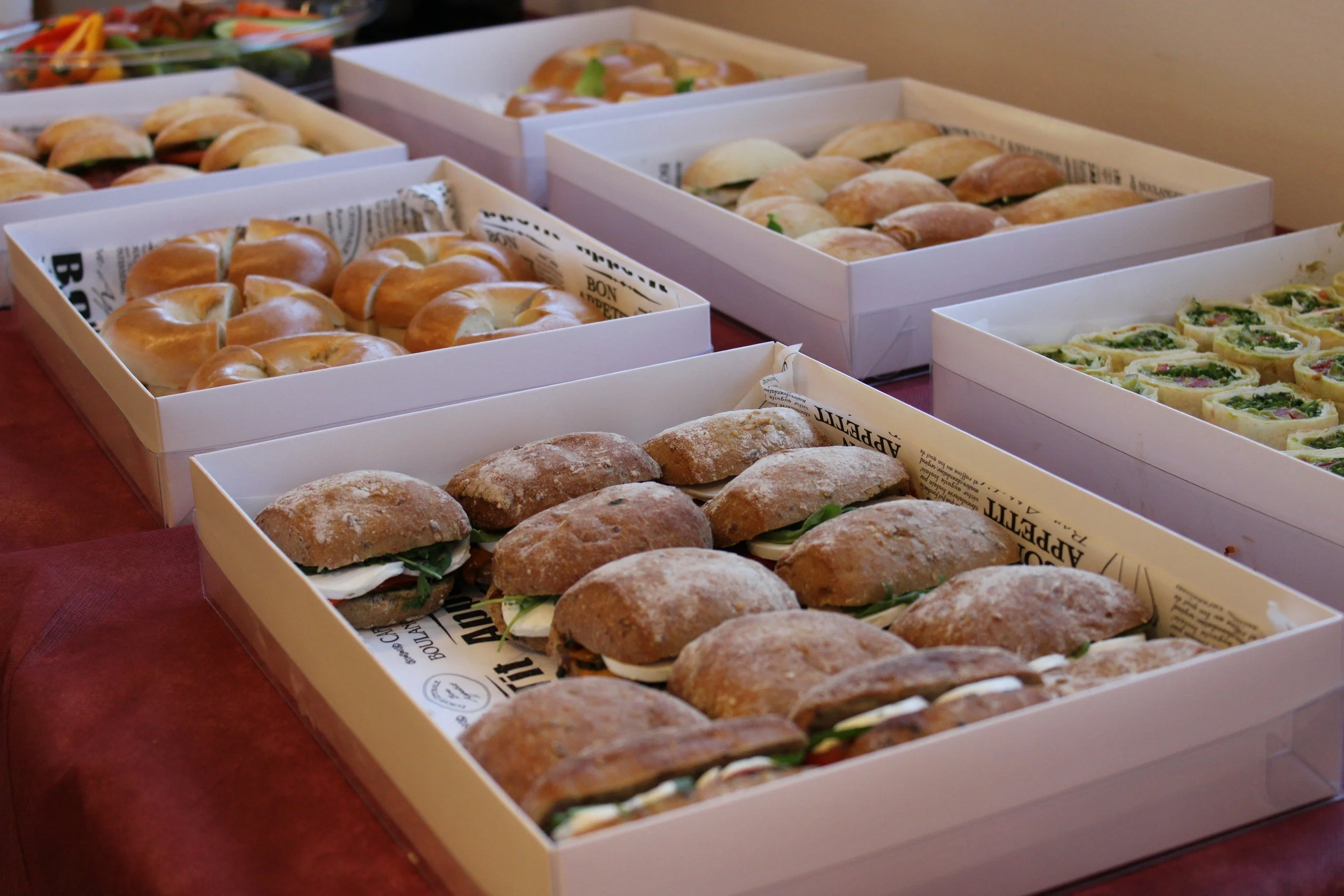 Assorted sandwiches and sliders arranged in white boxes on a table.