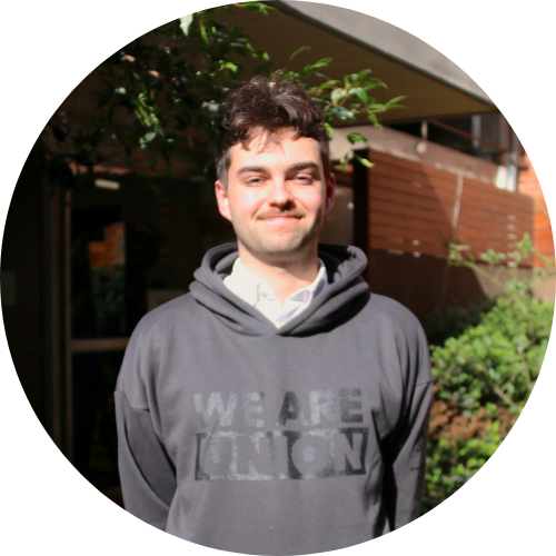 Young man wearing a dark hoddie that reads 'We Are Union' over a button up shirt.