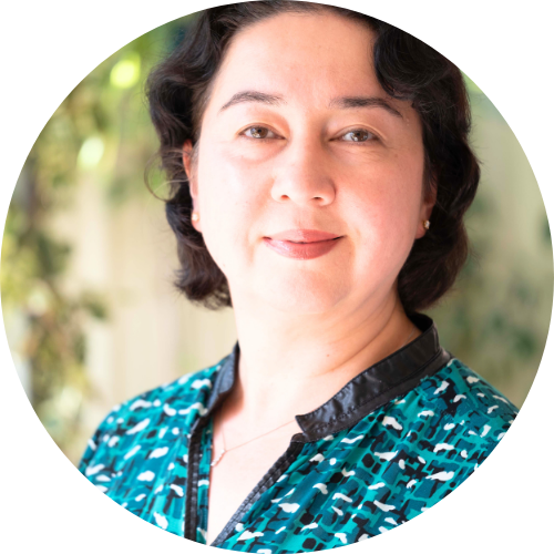 Ramila Chanisheff smiling, facing the camera, wearing a blue and white patterned shirt.