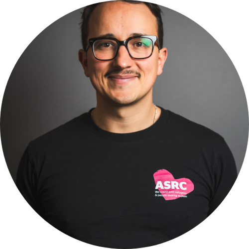 Portrait of Ogy Simic smiling, wearing a black shirt with the ASRC heart logo