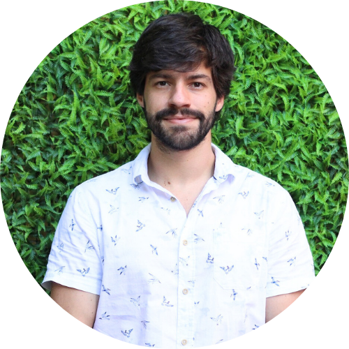 Portrait of Ricardo Borges Martins standing in front of a garden hedge, wearing a white shirt.