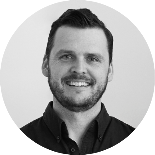 The image is a professional black-and-white headshot of Scott Sanders, shown smiling with short dark hair, a short beard, and a dark button-down shirt.