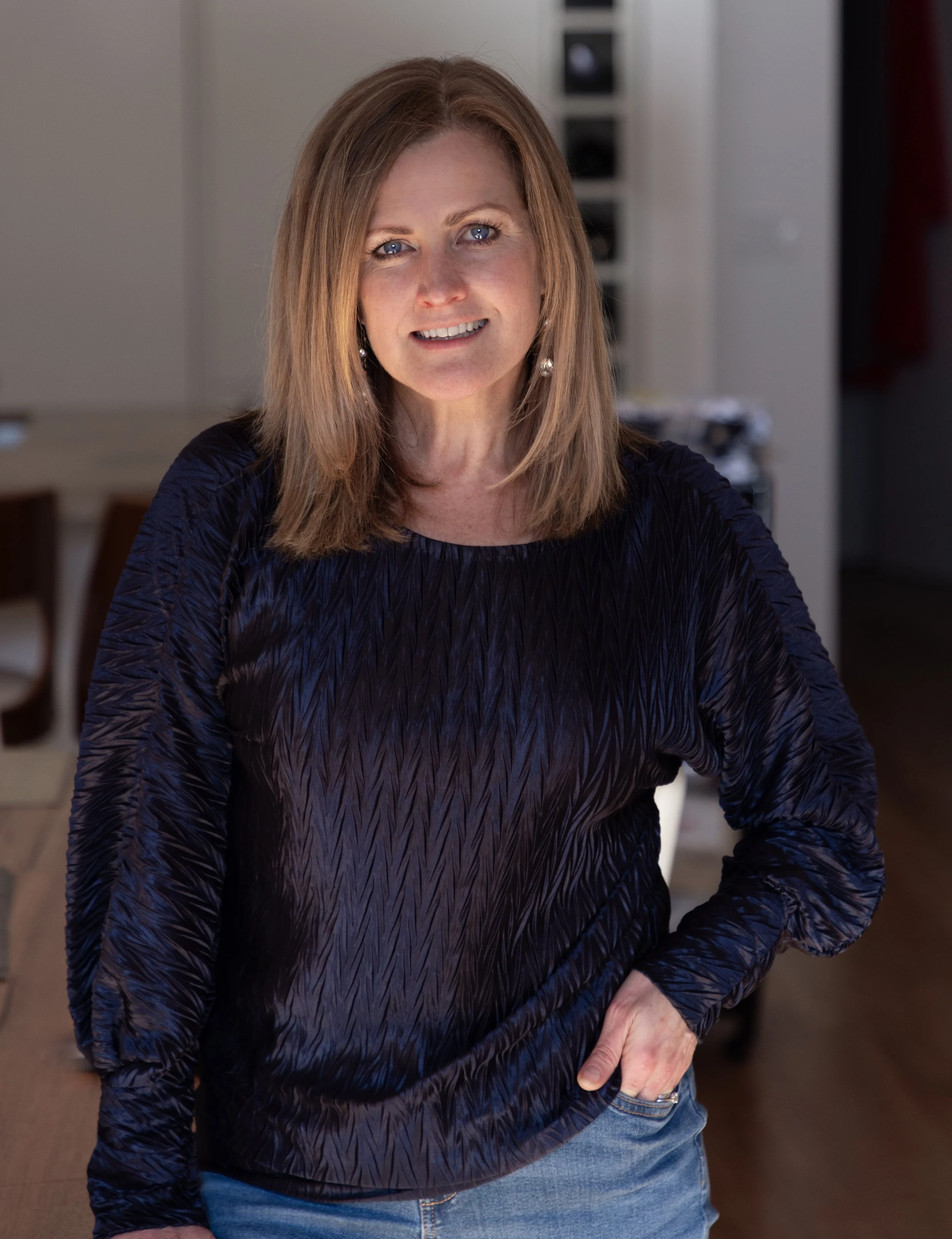 Katherine in a blue shirt with hand on hip