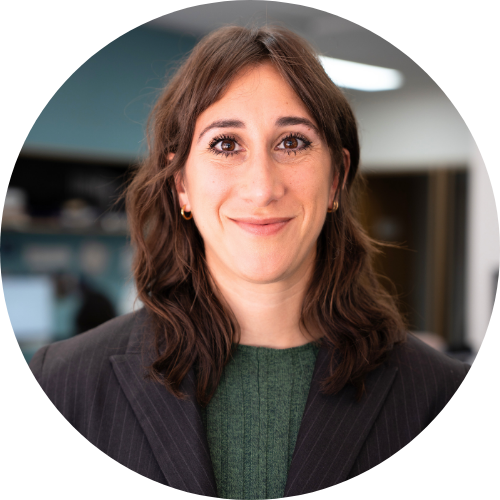 Portrait of Sarah Schwartz smiling, looking at the camera, wearing a black blazer.
