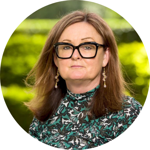 Jacqueline King, wearing dark glasses and a green and black floral shirt against a grassy background.