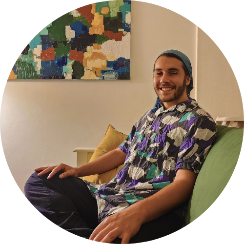 Portrait of Will Potter smiling, seated. He is wearing a patterned shirt.