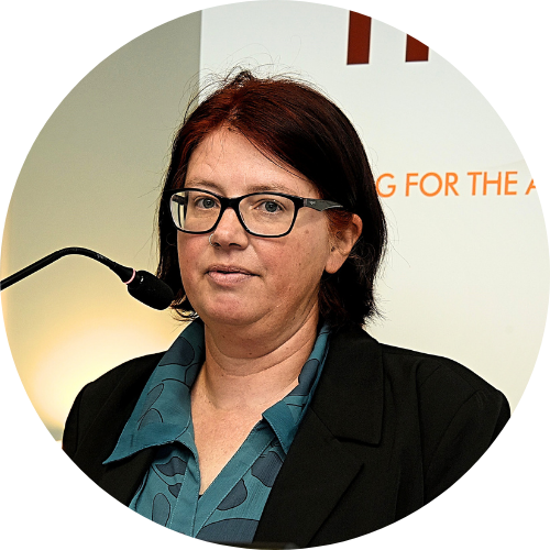 Fiona stands at podium with Housing for the Aged banner behind her.