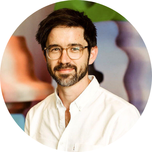 Chris Cooper, wearing white shirt against a colourful background