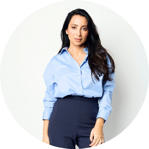 Antoinette Lattouf, wearing a blue collared shirt and navy pants, against a grey backdrop.
