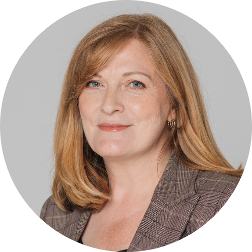 Portrait of Michelle Higelin smiling, facing the camera, wearing a checkered suit.