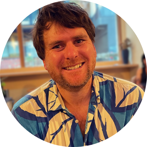 Portrait of Thomas Walker smiling at the camera, wearing a blue and yellow patterned shirt.