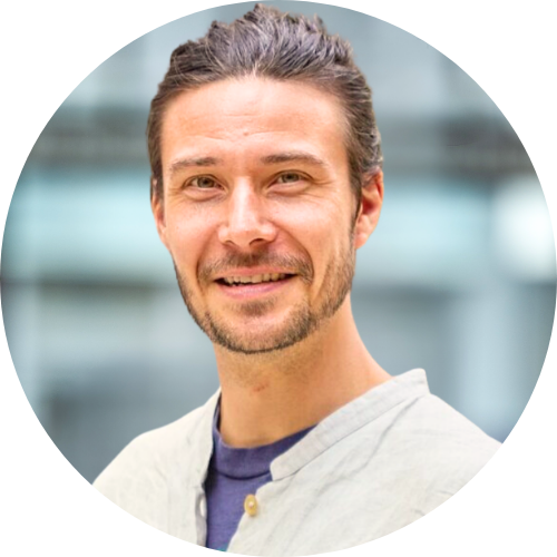 Portrait of Chris Patz smiling at the camera, wearing a white and blue shirt.