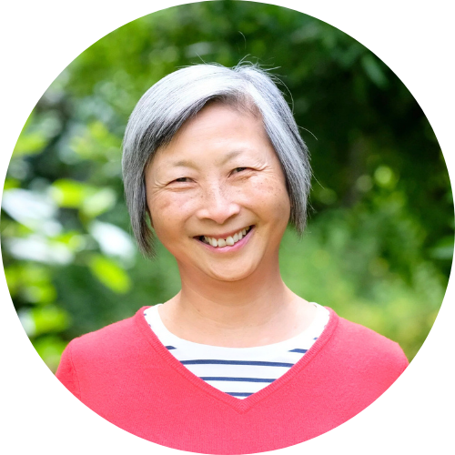 Anita Tang smiling, facing the camera, wearing a pink and black and white striped shirt.