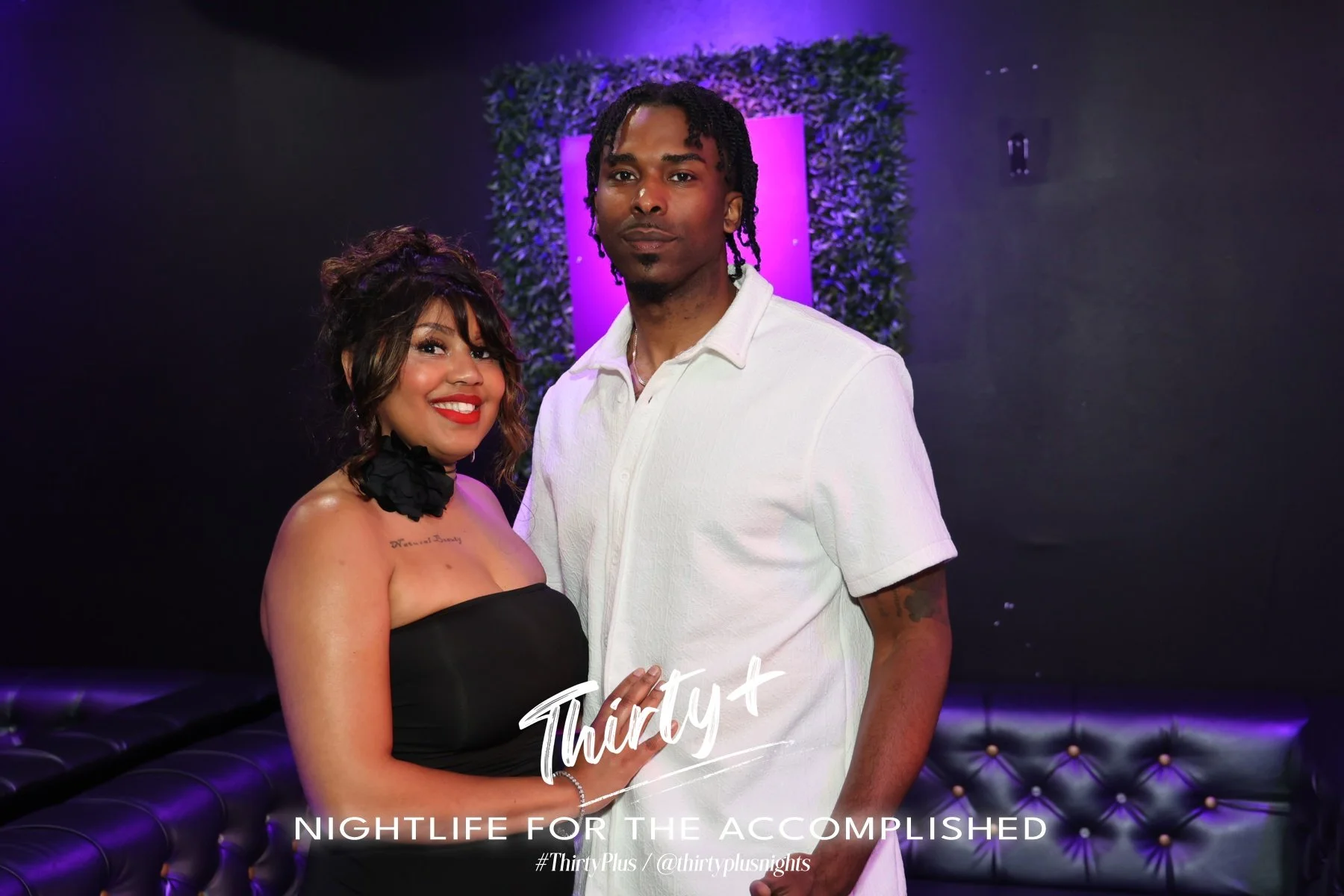 A man and a woman posing together inside a nightclub with purple lighting and a padded black booth. The woman is wearing a black strapless dress with a black floral neck accessory, and the man is dressed in a white short-sleeve shirt. They are standing close together, smiling at the camera. The image features text that says "Thirty+ NIGHTLIFE FOR THE ACCOMPLISHED" along with hashtags and social media handles.