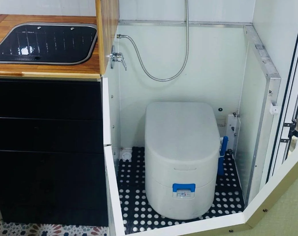 Small bathroom with a black sink, a compact washing machine, and a handheld showerhead mounted on the wall.