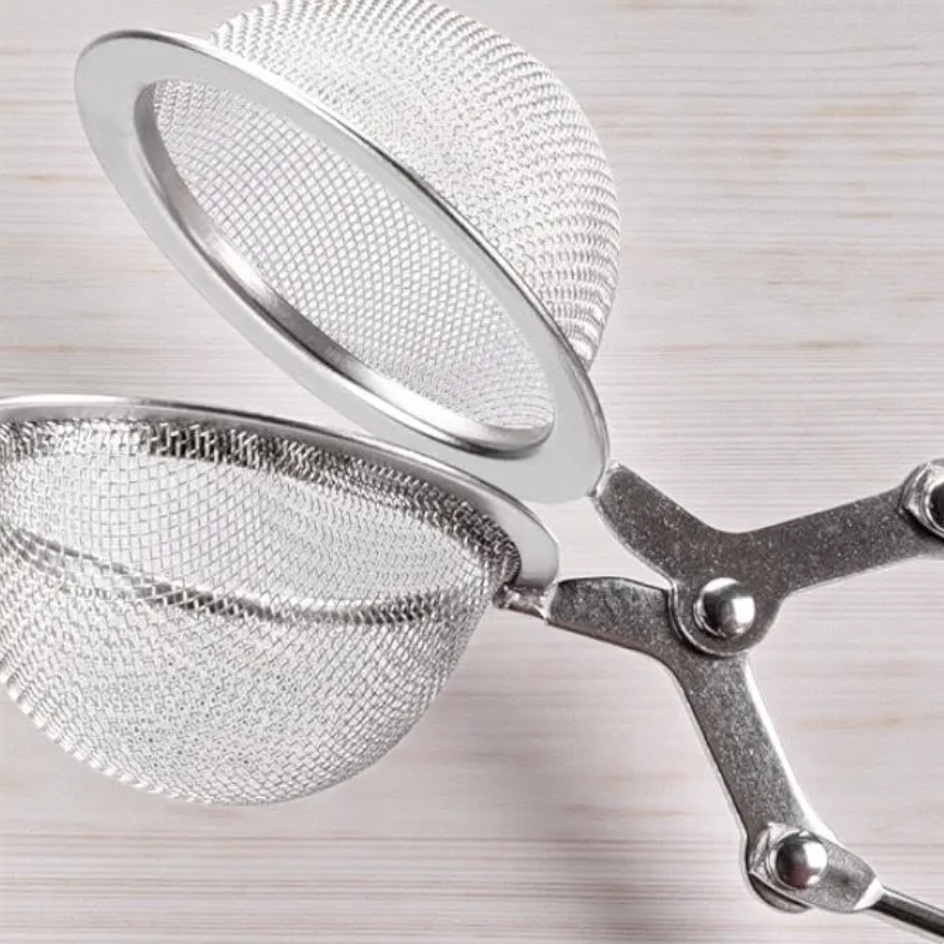 Open stainless steel tea strainer lying flat on table ready for loose leaf tea