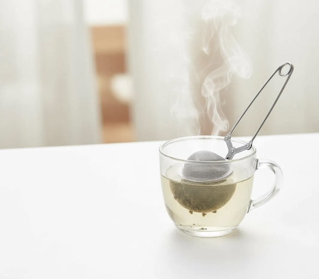 Close-up of tea strainer filled with loose herbal tea leaves making a cup of tea