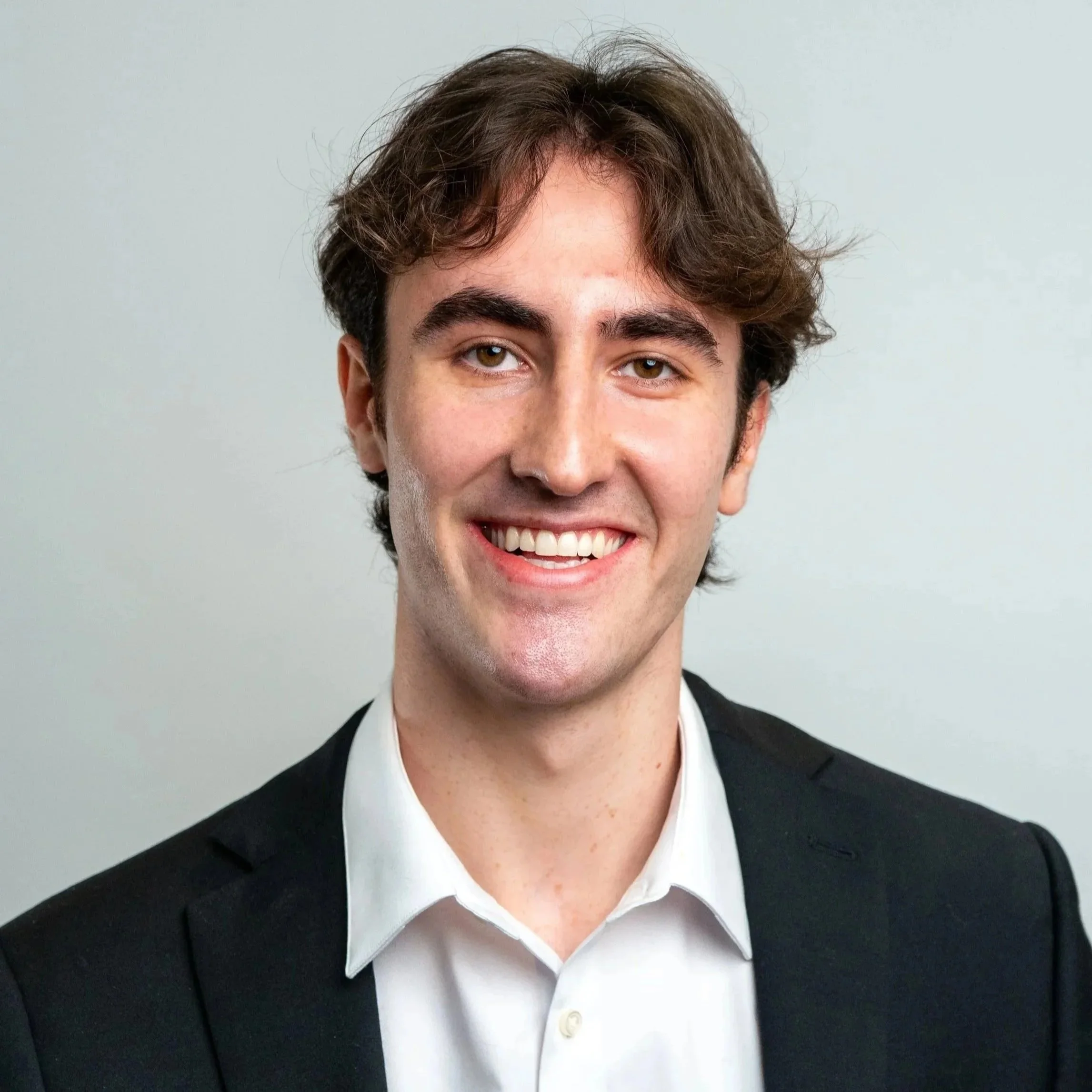 A man operating a professional film camera with a woman watching beside him in a dimly lit room.