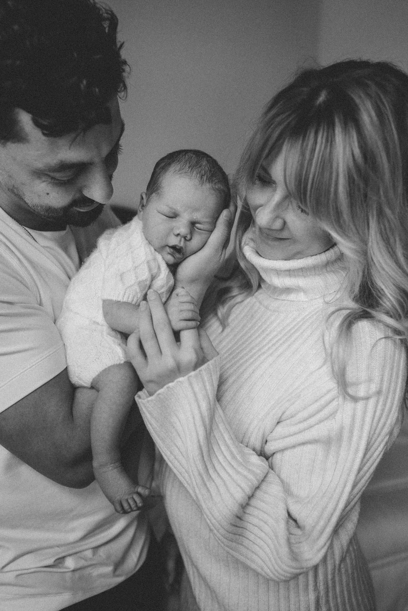 Black-and-white portrait of loving parents holding their sleeping newborn baby during a Seattle lifestyle newborn photography session.