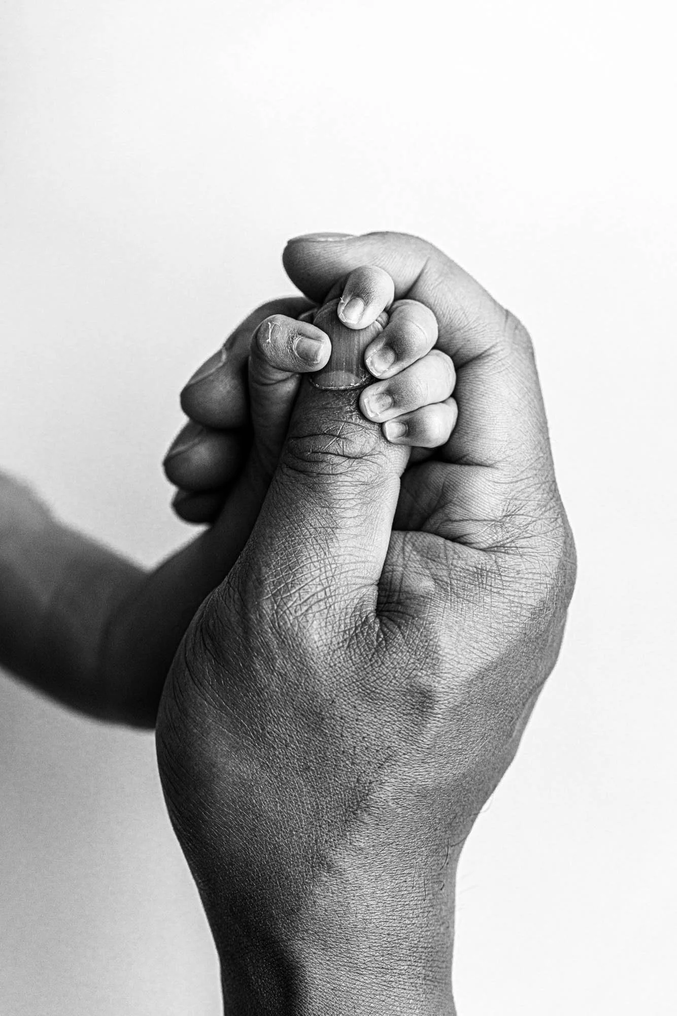 Black-and-white close-up of a baby’s hand wrapped around a parent’s finger during a Seattle milestone photography session.