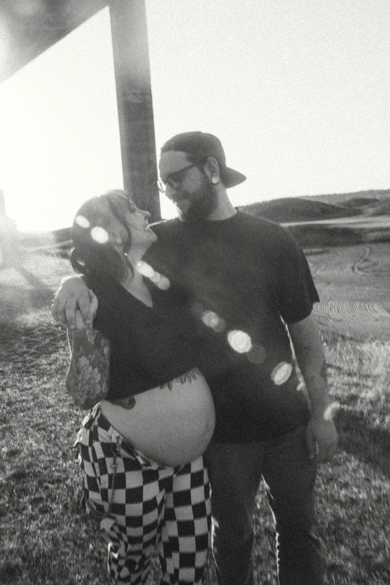 Black-and-white portrait of an expectant couple embracing during a sunset maternity session in Tacoma.